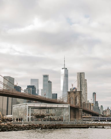 Brooklyn Bridge and Manhattan skyline with modern glass towers and waterfront carousel pavilion