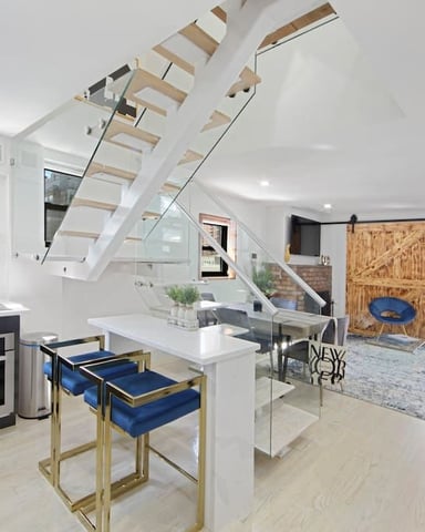Modern loft with open-plan kitchen, dining area, and living space with floating staircase and city view window