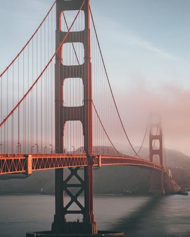 Golden Gate Bridge spanning San Francisco Bay at sunrise with fog rolling in